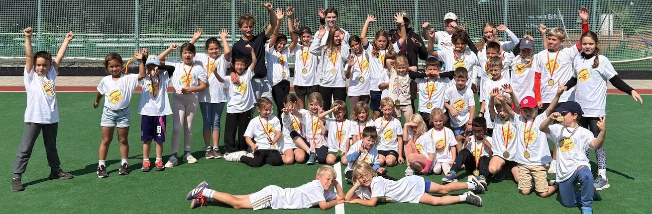 Ferienprogramm-und-Feriencamps_Kidz-Multisport-Camps_M_2 Gruppenbild Kinder im Sport Feriencamp & Ferienprogramm jubeln, mit Shirts und Medaillen, gutgelaunt.